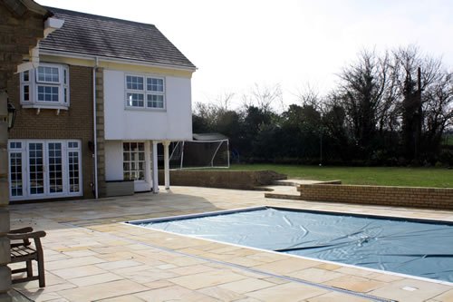 Manuden — the finished scheme seen from the far side of the pool, the terrace tying the house, the pool and the lawn together.