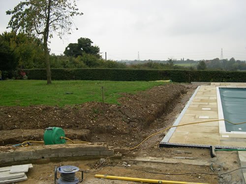 Manuden — mid-build: the old paving lifted and taken away, the ground dug out and services run before any of the new stone went down.