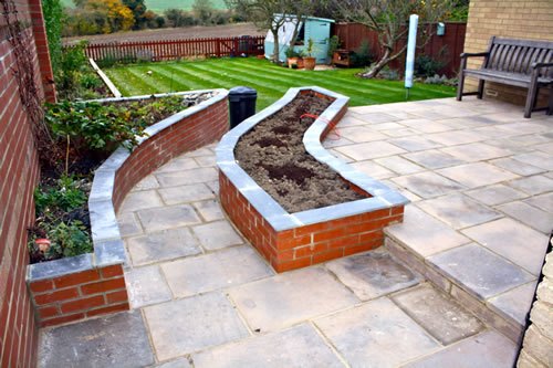 Saffron Walden — the rear garden completed: a stone terrace, a raised brick bed, a shaped lawn and a bench set at the far end.