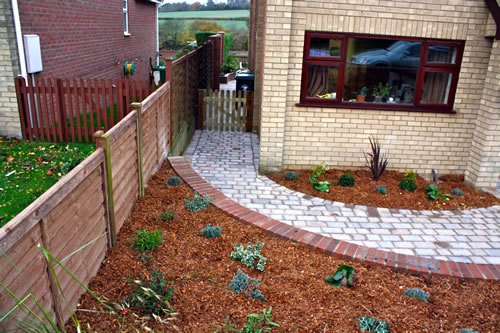 Saffron Walden — a setts-and-slab path running down the side return, with new planting set into a mulched bed against a new close-board fence.
