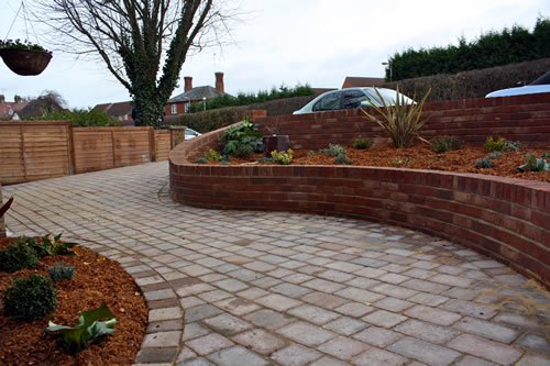 Saffron Walden — a curved brick retaining wall wrapping a new bed, with the paving cut in cleanly to follow the line.